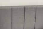 Gray upholstered headboard with pleated design on a plain background