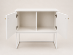 A white wooden sideboard cabinet with two doors swung open to show the interior shelving, set against a plain light beige background.