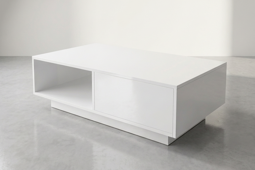 A modern white rectangular coffee table with a single open shelf and a front storage drawer, set on a gray concrete floor against a minimalist white wall with soft sunlight.