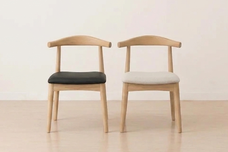 Two wooden chairs with cushioned seats on a light wooden floor.