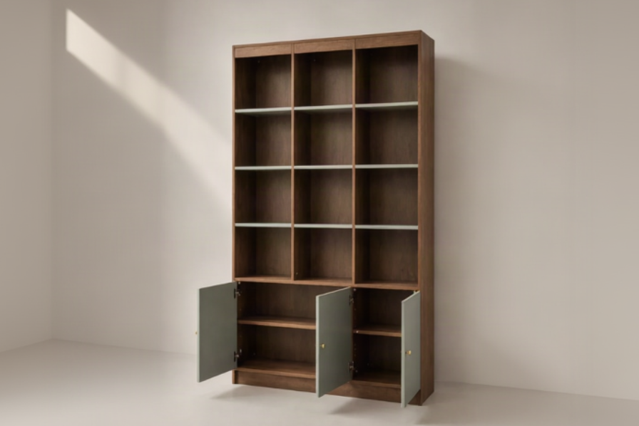 A tall wooden bookcase with a warm medium-brown finish, featuring twelve open shelves and two lower cabinet doors in a muted sage green color, shown open on a light neutral studio background.