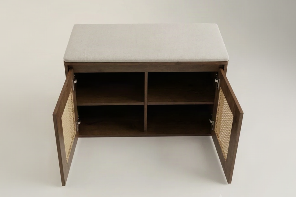 A dark brown wooden entryway bench with a light gray upholstered cushion on top and two cane-finished doors swung open to reveal open storage shelves inside, photographed against a neutral light gray studio background.