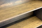 Close-up of a wooden shelving unit with three rustic, medium-brown wood shelves and a matching wood backing.