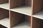 Close-up of a modular shelving unit with dark brown wood grain side panels and light beige shelves.