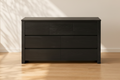  one black drawer on a wooden floor with a neutral wall background.