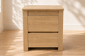 Wooden nightstand with two drawers in a room with sunlight casting shadows on the floor.