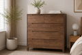 Wooden drawer in a bedroom with a bed, nightstand, and decorative items.