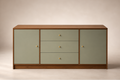 A mid-century modern sideboard cabinet with sage green doors and drawers, a warm brown wood frame, and small brass knobs, set against a neutral beige background.