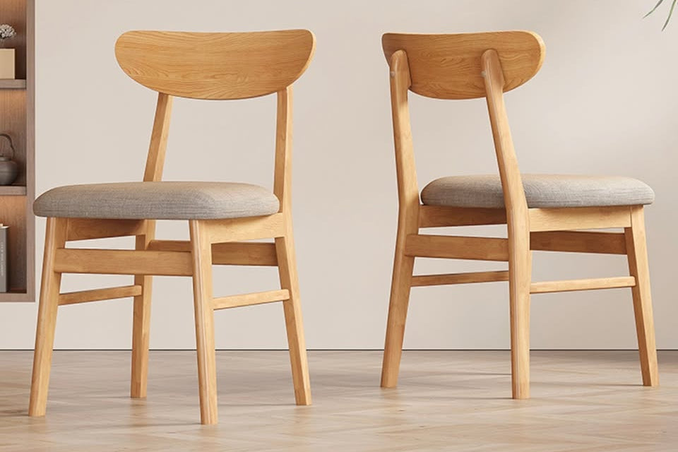 Two wooden chairs with gray cushions on a light wooden floor.