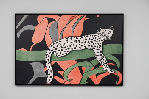 A framed art print featuring a stylized white spotted leopard with black spots, set against a background of large coral-pink and green abstract leaves on a black field, hung on a light gray wall.