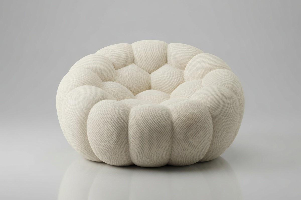 A round, low-profile pouf or accent chair upholstered in a textured cream fabric, featuring a segmented, flower-like petal design, set against a neutral gray background.