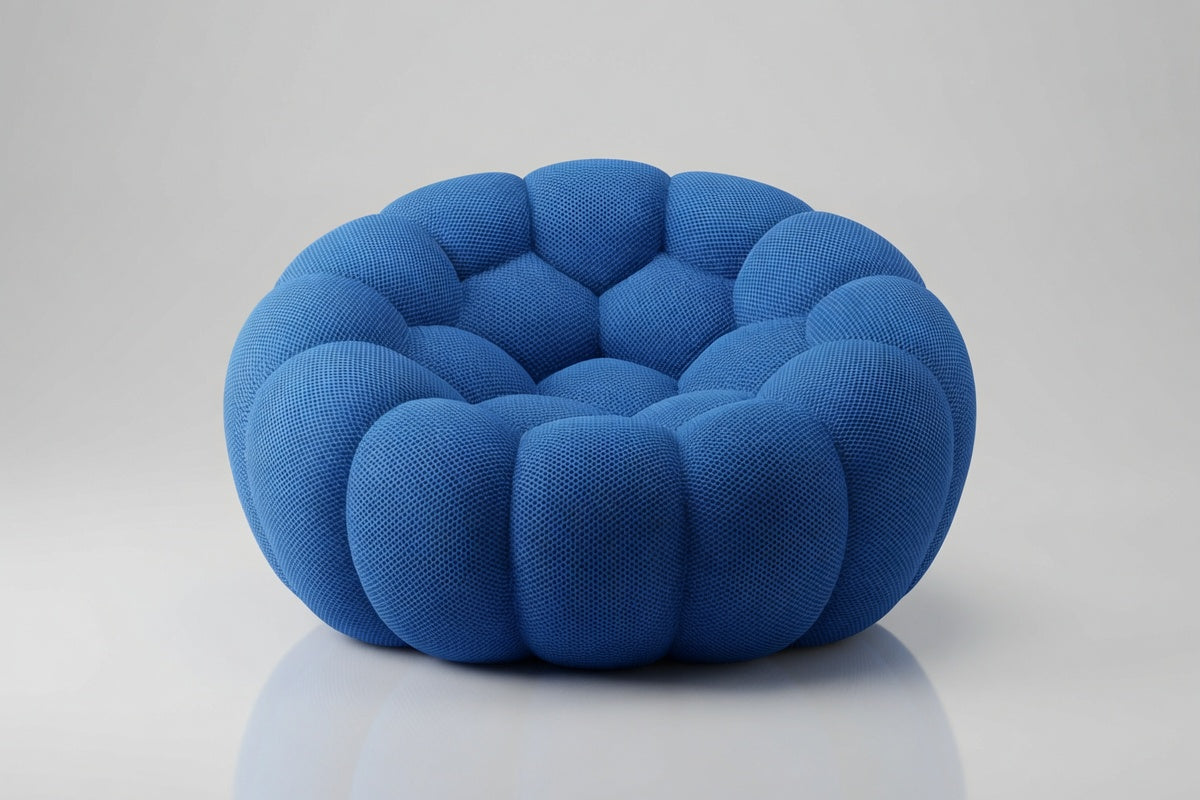 A modern, circular floor cushion or pouf in a textured blue fabric, featuring a segmented, scalloped outer edge and a tufted center, set against a light gray studio background.
