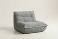 A compact, low-profile modular floor cushion chair in a textured gray fabric, photographed on a seamless light beige studio background.