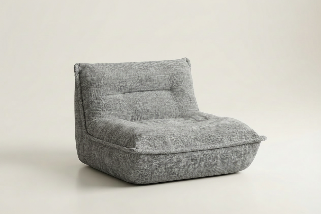 A compact, low-profile modular floor cushion chair in a textured gray fabric, photographed on a seamless light beige studio background.