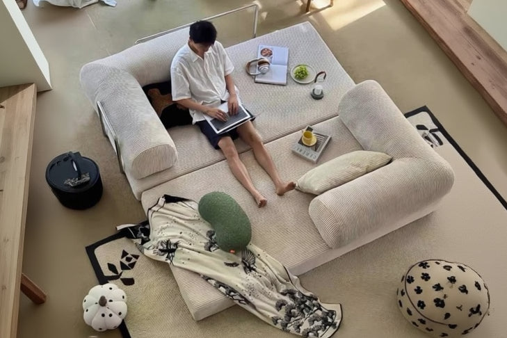 Person sitting on a large beige sofa in a modern living room.